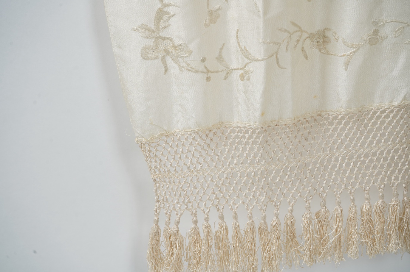 An early 20th century Chinese cream on cream silk embroidered, fringed stole, 65cm wide. Condition - some light staining.
